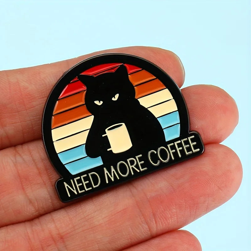 Hand holding Need More Coffee cat brooch pin—retro rainbow enamel brooch for coffee lovers.