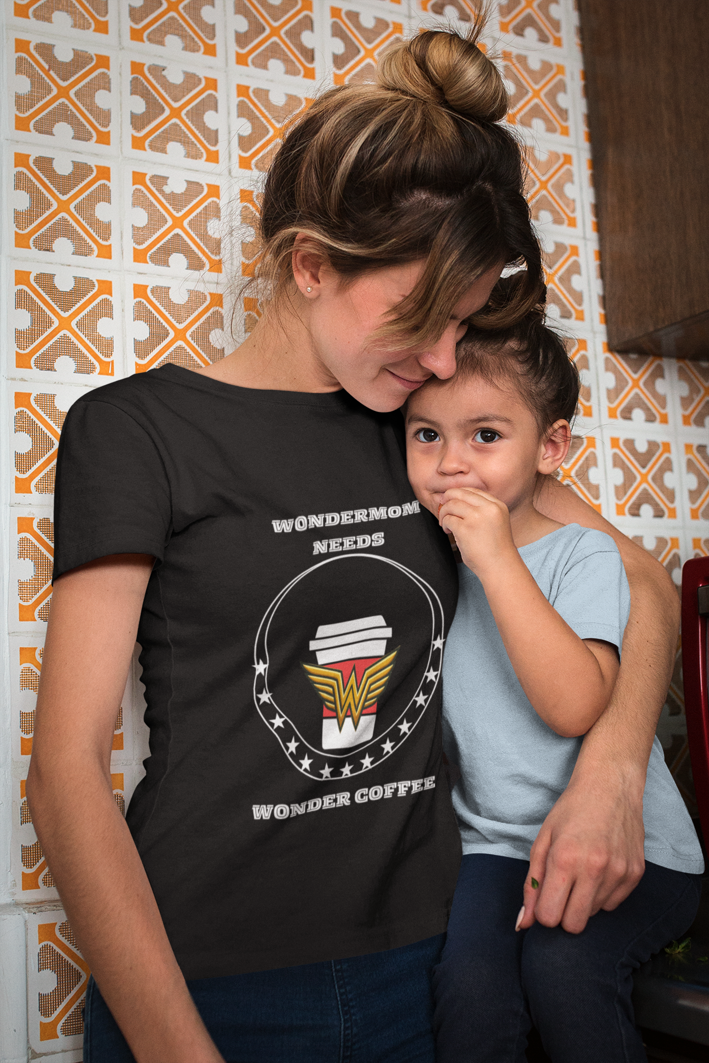 Black funny mom shirts style tee reading “WonderMom Needs Wonder Coffee” worn by mom cuddling toddler in cozy kitchen.