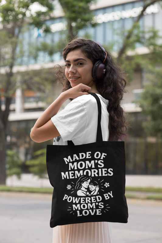 	Smiling woman wearing headphones and carrying black tote bag with “Made of Mom’s Memories Powered by Mom’s Love” design.