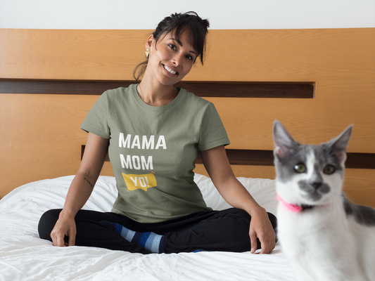 Green “Mama Mom Yo!” mom life shirt modeled by relaxed mom on bed while curious cat looks on.