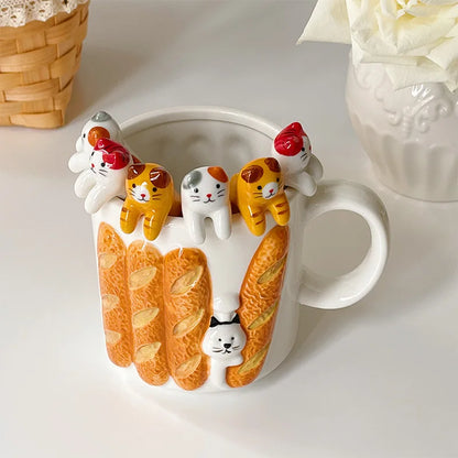 White mug with baguette design and six cat coffee spoons hanging around the edge—whimsical kitchen funny gifts display.


