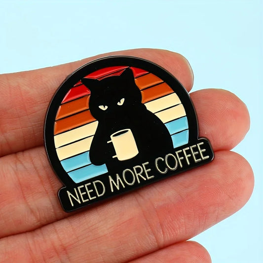 Hand holding Need More Coffee cat brooch pin—retro rainbow enamel brooch for coffee lovers.