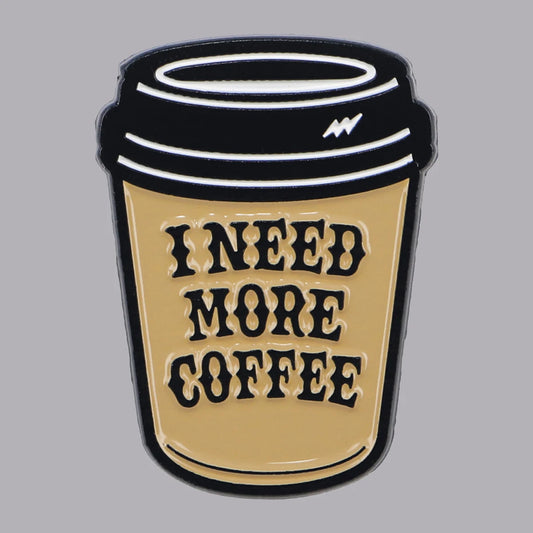 I Need More Coffee enamel brooch shaped like a takeaway coffee cup, cream and black hard‑enamel pin.