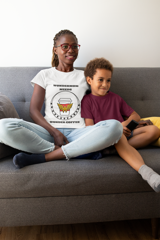 Mom life shirt featuring “WonderMom Needs Wonder Coffee” graphic worn by smiling mom sitting on couch with her young son.