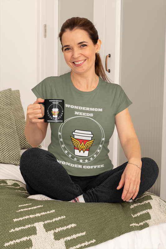 Funny mom shirts design “WonderMom Needs Wonder Coffee” shown on green tee as mom relaxes on bed holding a matching coffee mug.